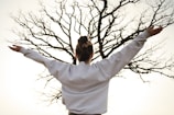 woman in white long sleeve shirt standing near bare tree during daytime