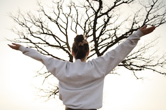 woman in white long sleeve shirt standing near bare tree during daytime