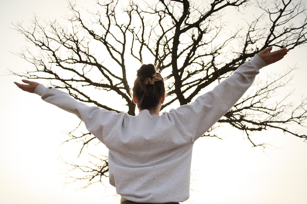 woman in white long sleeve shirt standing near bare tree during daytime