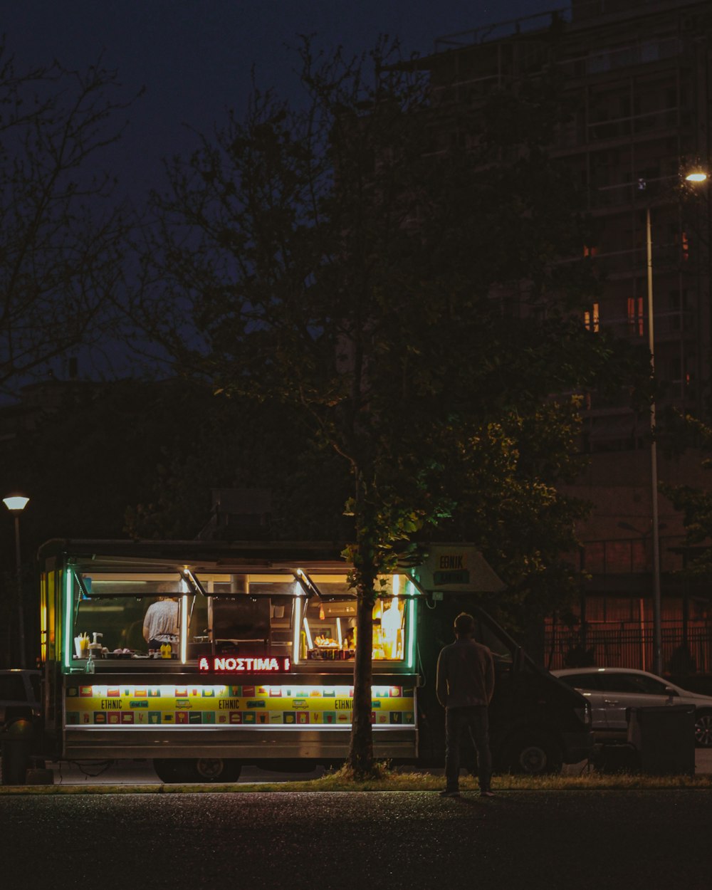 um homem em pé na frente de um caminhão de comida à noite