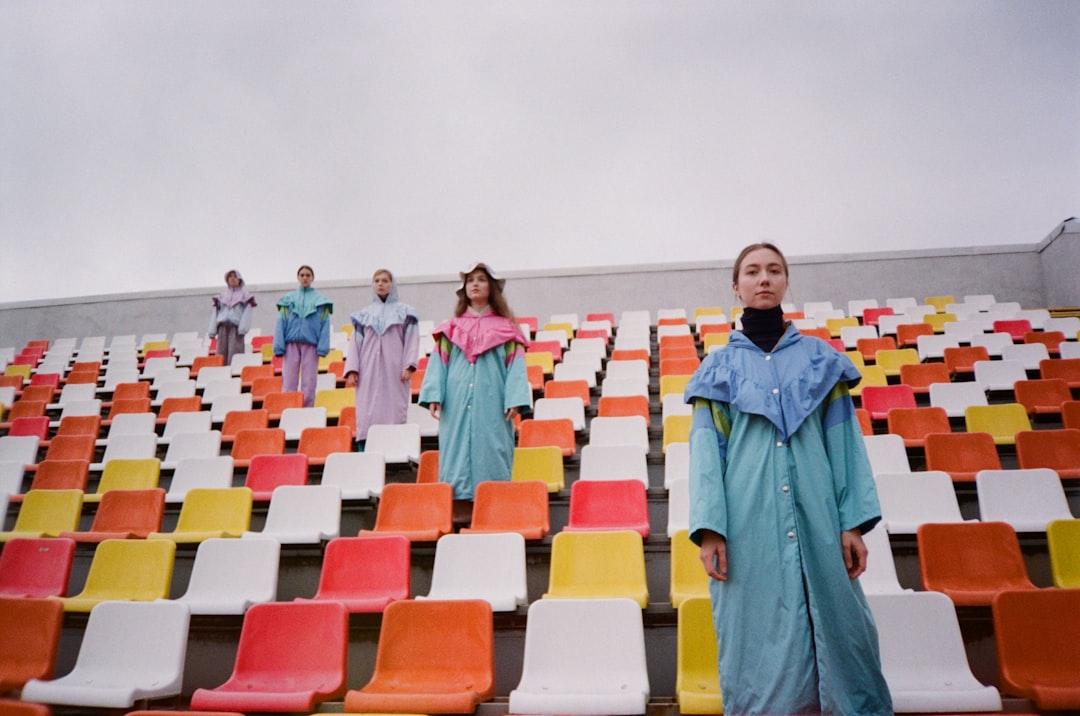 group of people standing on red yellow and blue plastic chairs