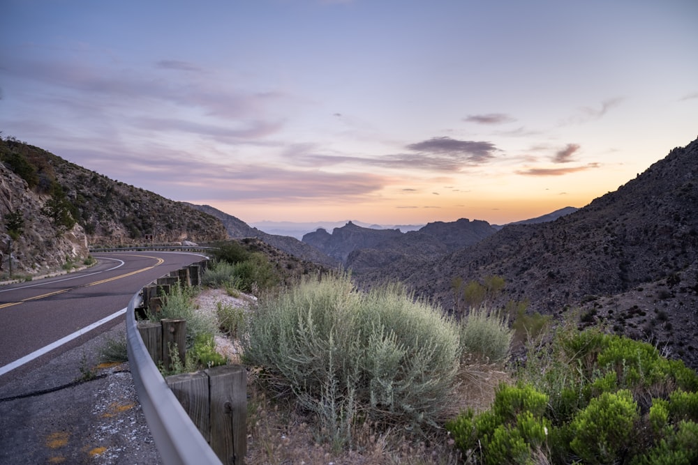 a winding road in the mountains at sunset