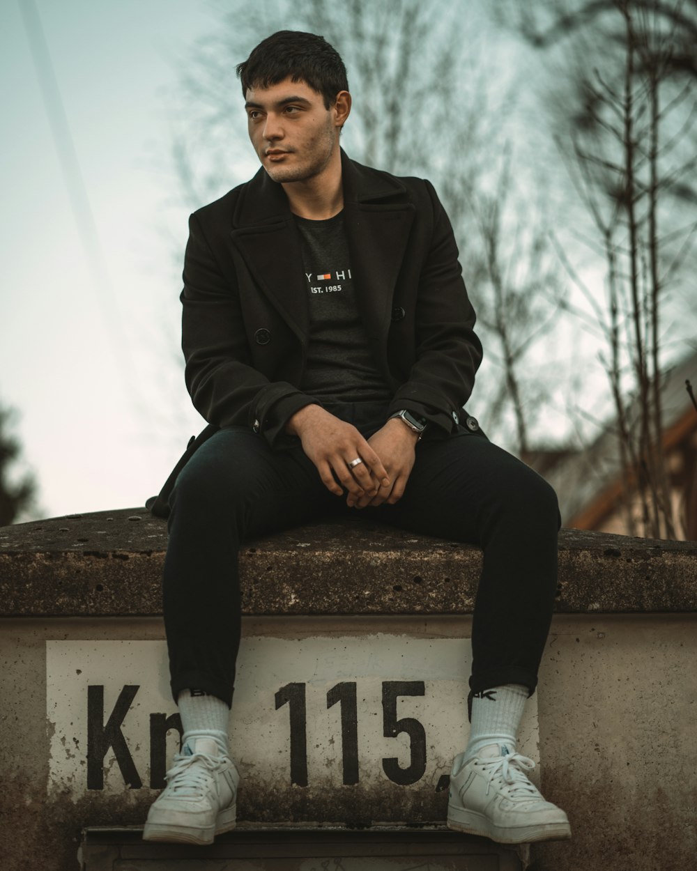 man in black leather jacket sitting on concrete bench