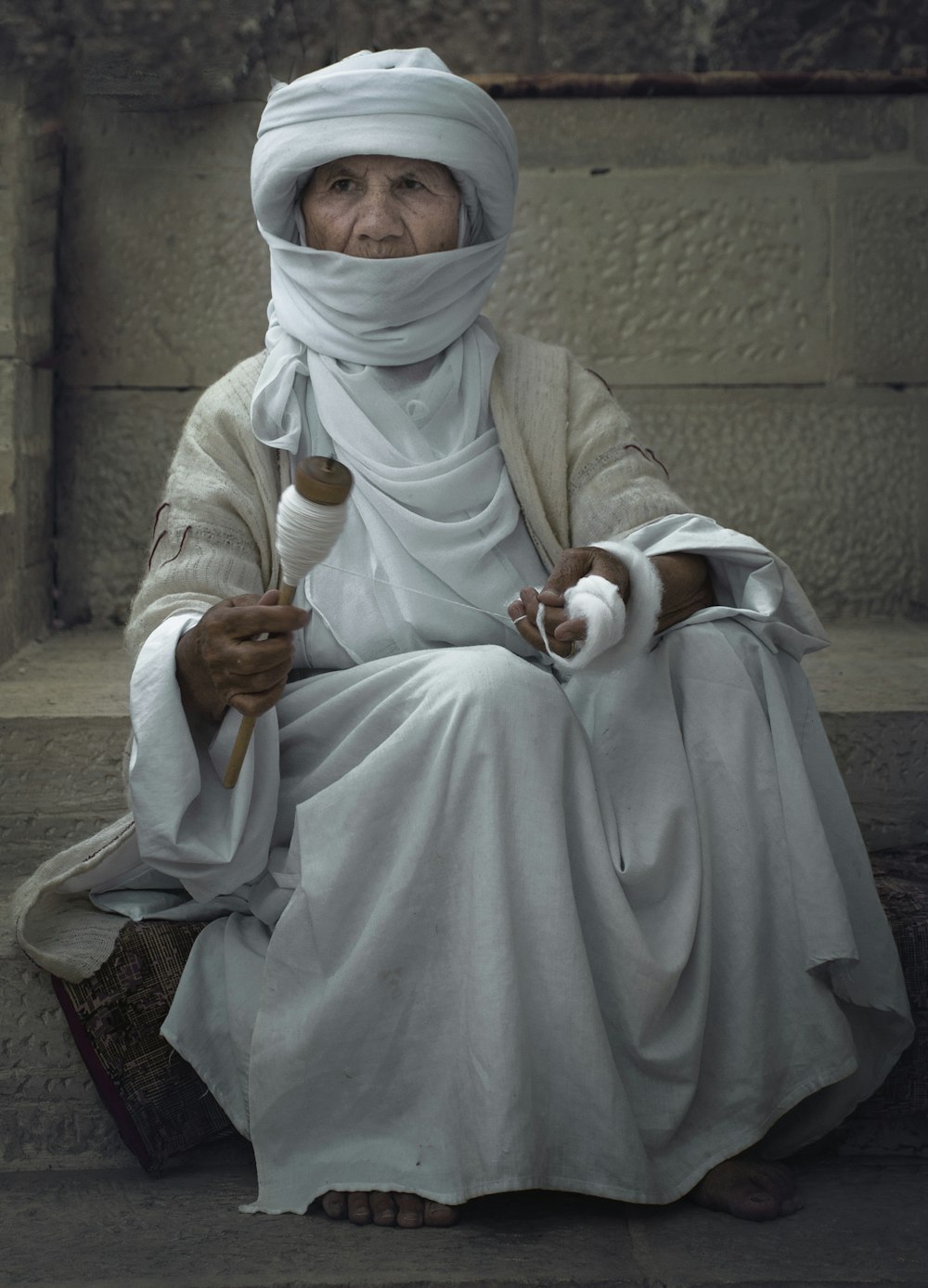 man in white thobe sitting on brown concrete stairs