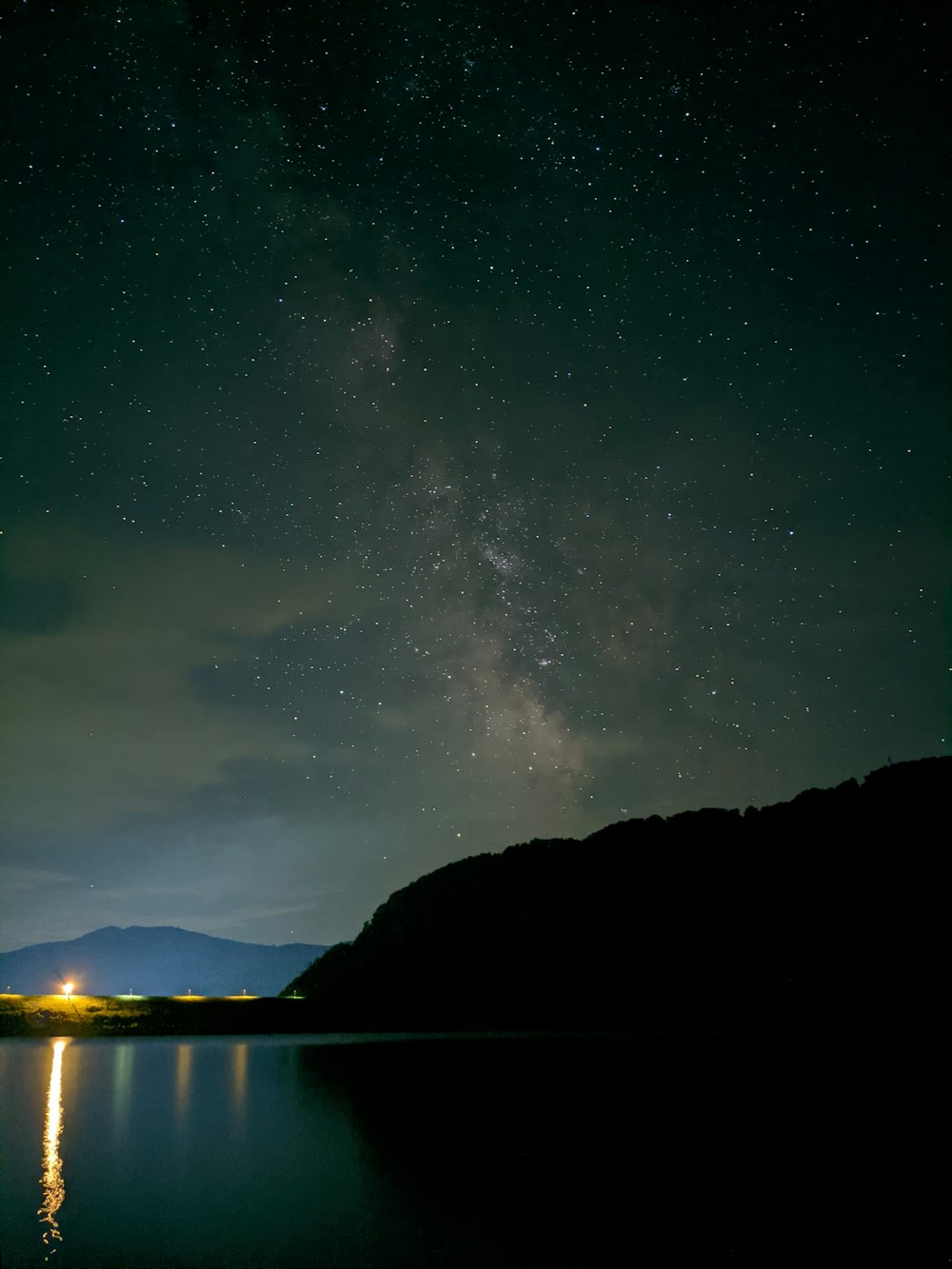 body of water near mountain during night time