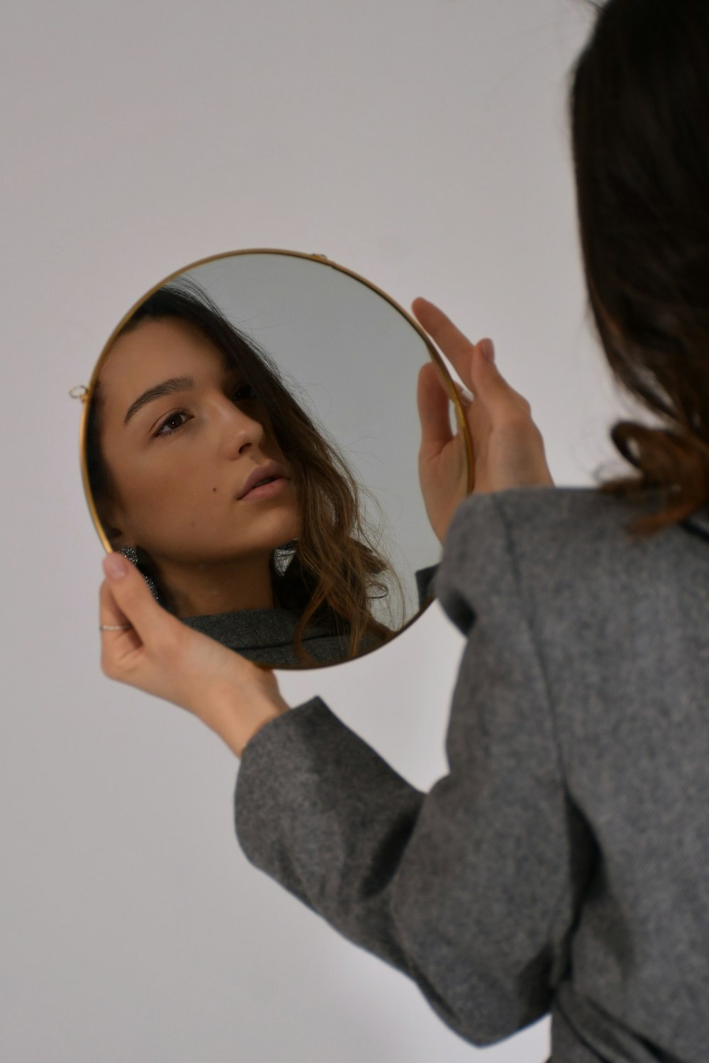 woman in gray long sleeve shirt holding her head