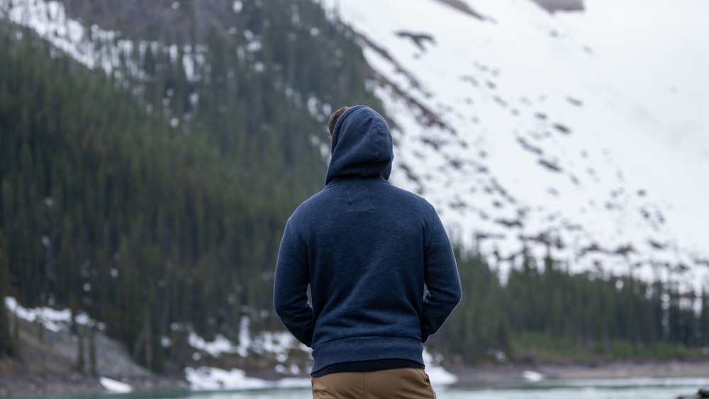 man in black hoodie standing on snow covered ground