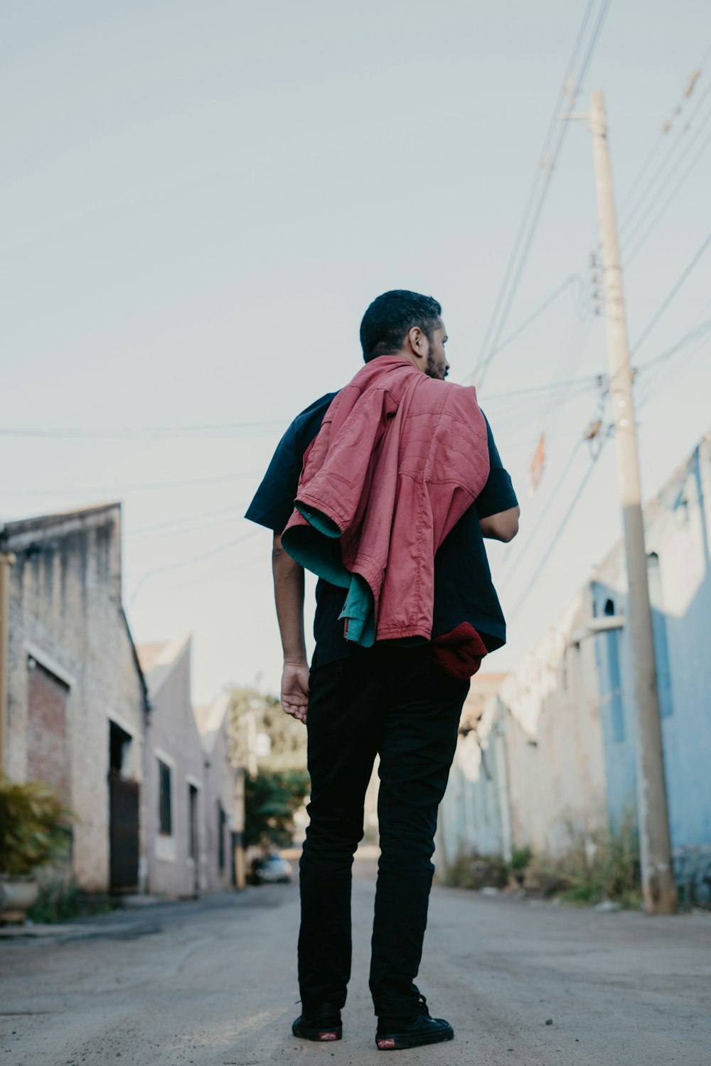 man in red t-shirt and black pants standing on pathway during daytime