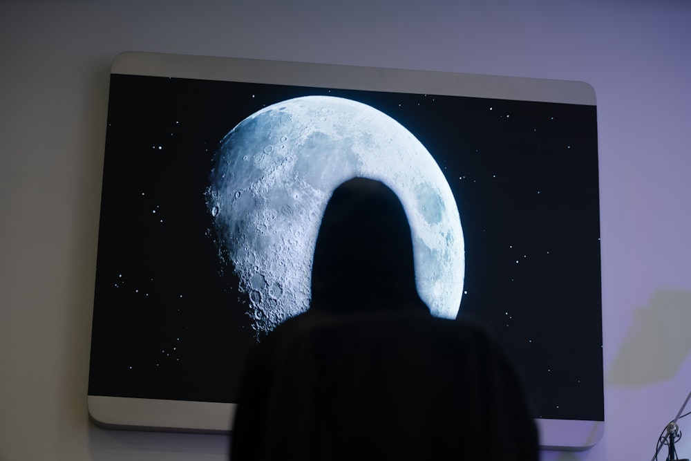 a person standing in front of a picture of a moon