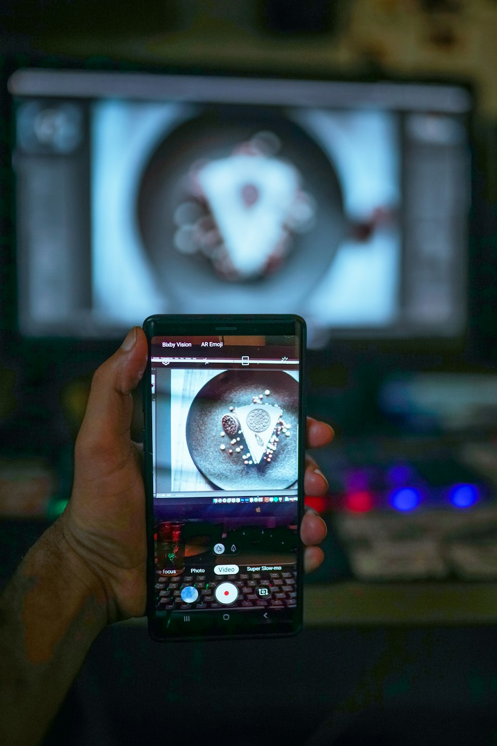 a person holding a cell phone in front of a tv