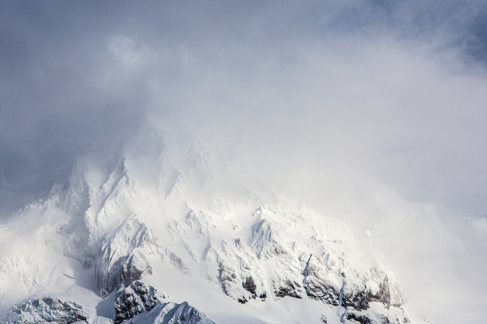 a mountain covered in snow under a cloudy sky