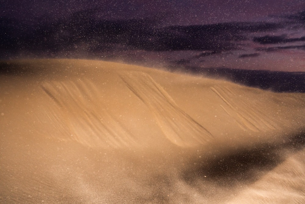 a sand dune with a purple sky in the background