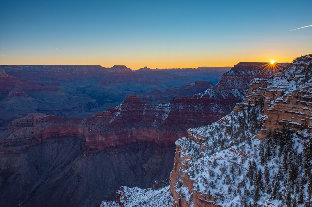 the sun is setting at the edge of the grand canyon