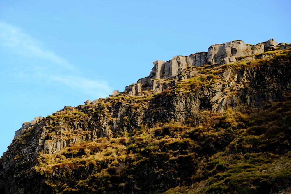 Montaña rocosa verde y marrón bajo el cielo azul durante el día