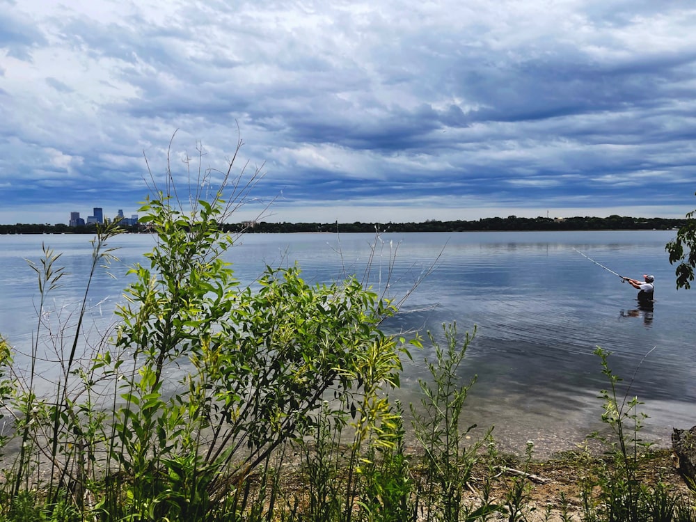 Un hombre parado en el agua sosteniendo una caña de pescar