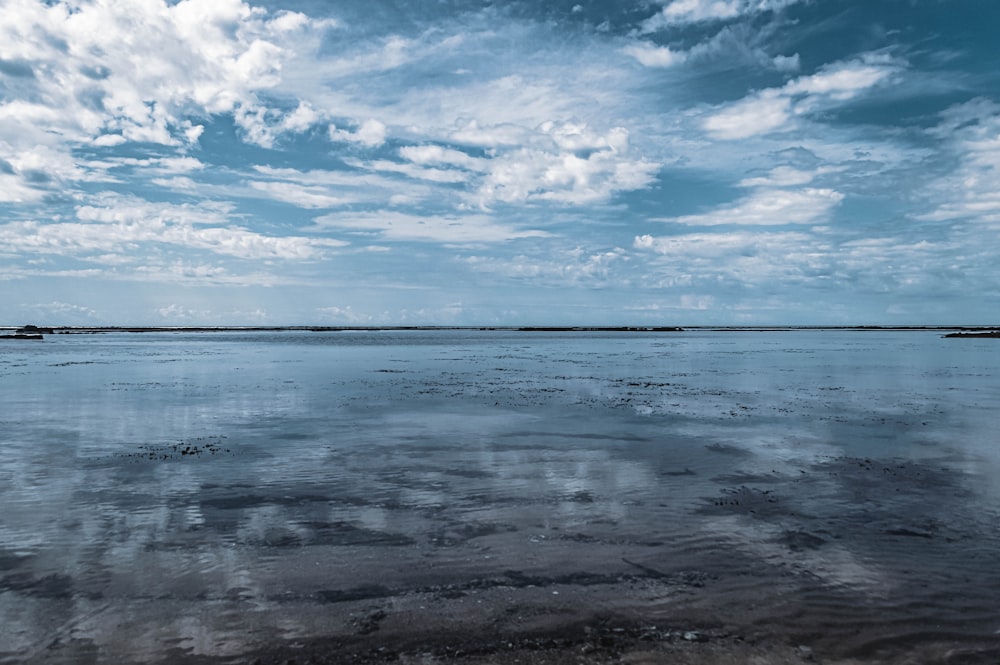 a large body of water sitting under a cloudy blue sky