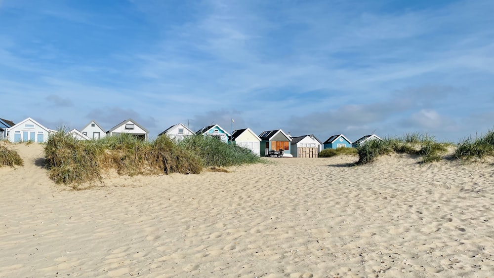 une rangée de cabanes de plage assises au sommet d’une plage de sable