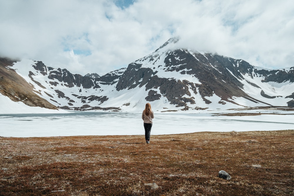 a woman standing in a field with a mountain in the background