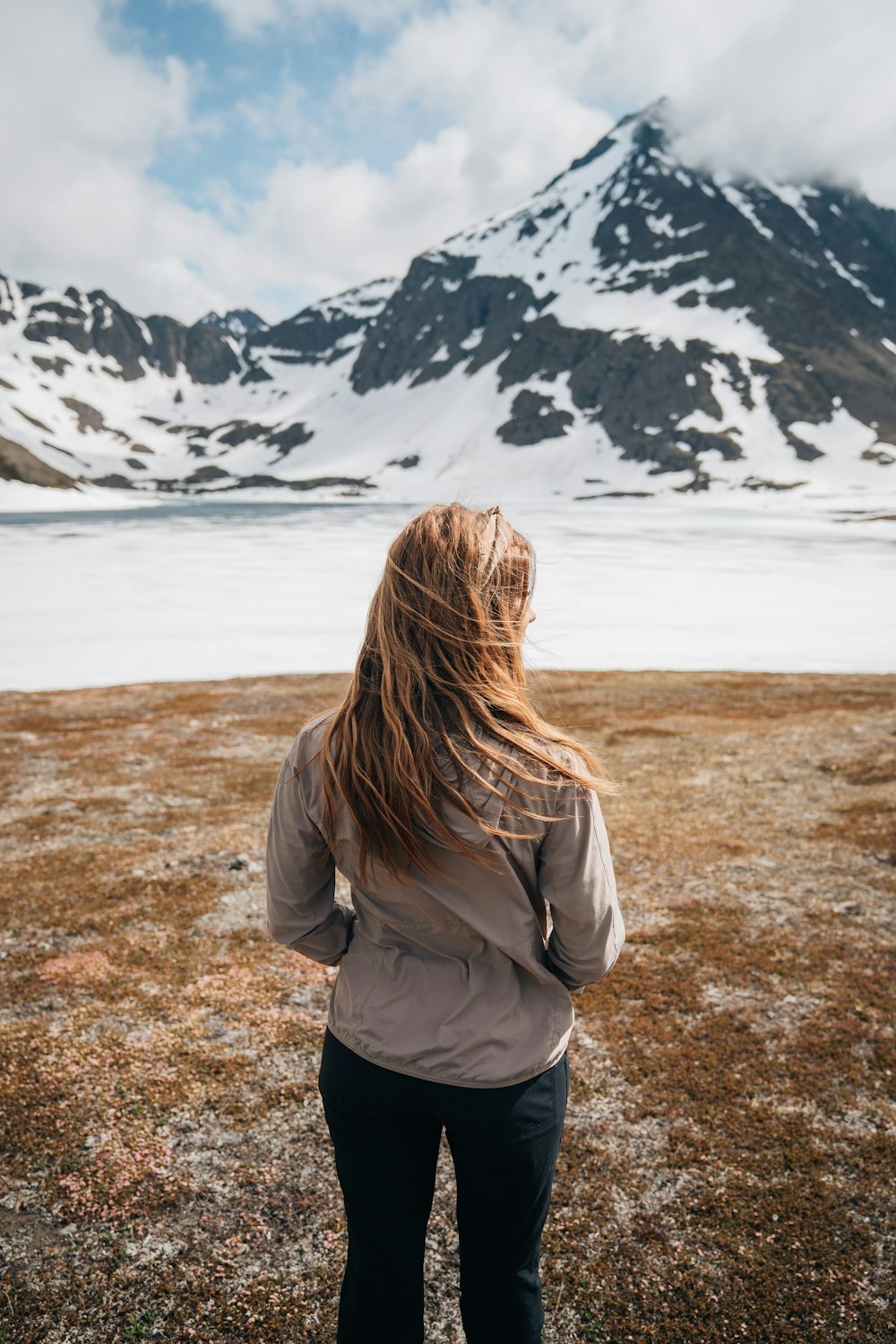 a woman standing in a field with a mountain in the background