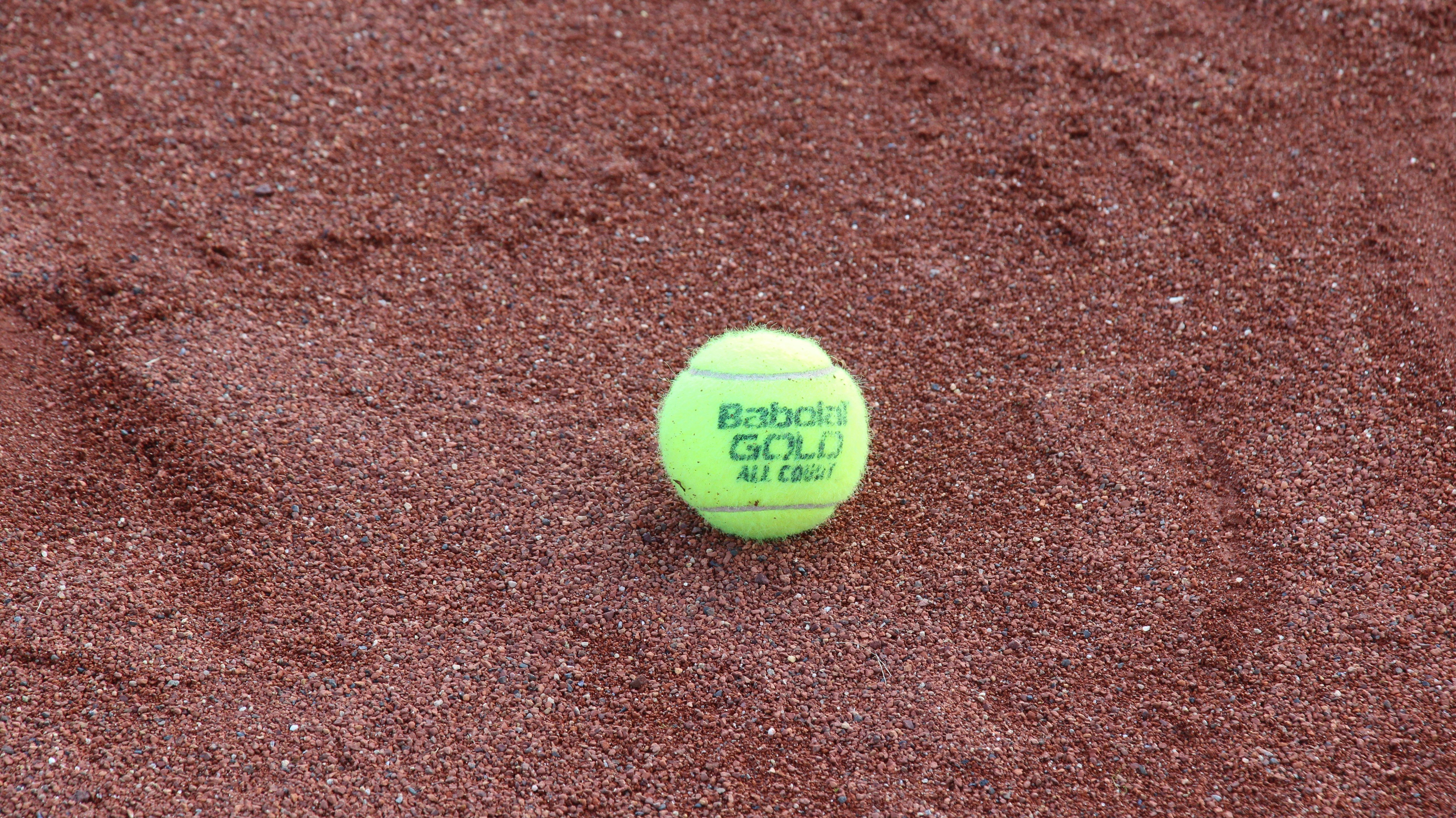 yellow tennis ball on brown textile