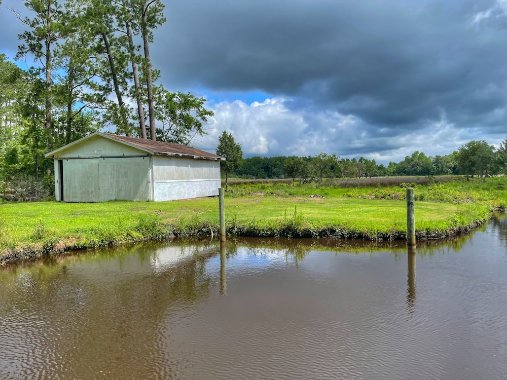 white wooden house beside green grass field and body of water during daytime