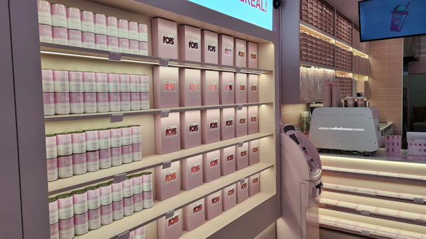 Organized shelves stocked with coffee pods, creamers, and snacks in a bright office pantry.