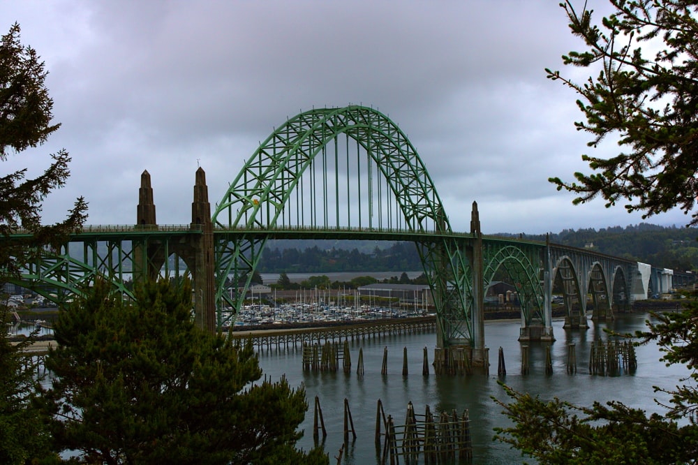 green metal bridge over river under white clouds