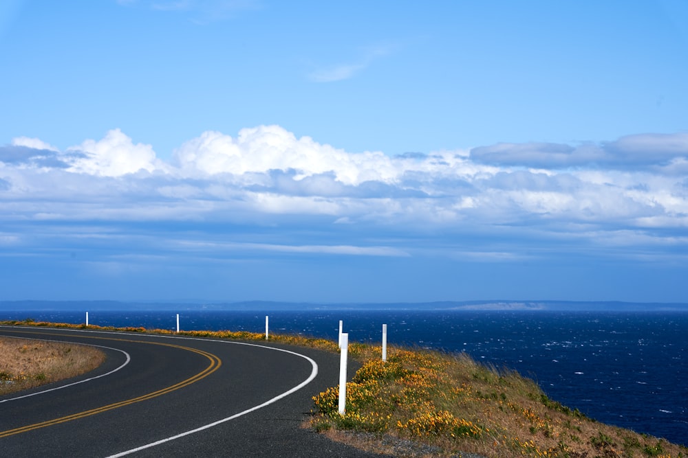 a curved road on the side of a hill next to the ocean