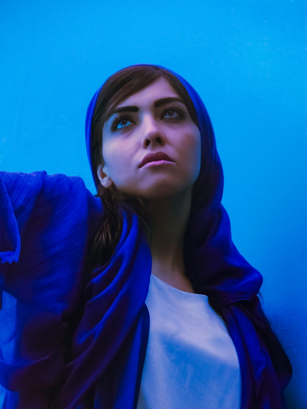 a woman wearing a blue shawl standing in front of a blue wall