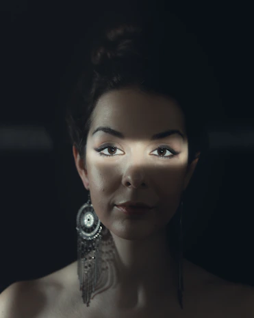 Editorial-style portrait of a model wearing statement earrings, framed by soft shadows and clean lines.