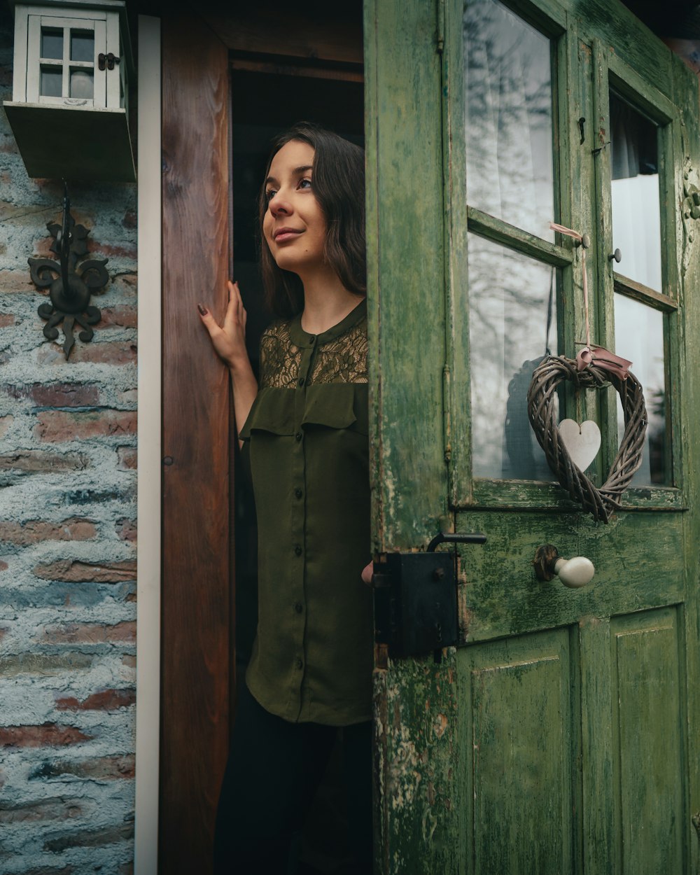 woman in black and brown floral sleeveless dress standing beside green wooden door