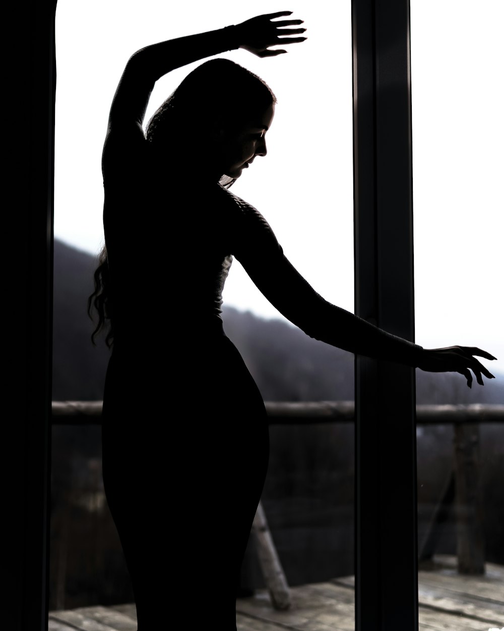 woman in black dress standing by the window