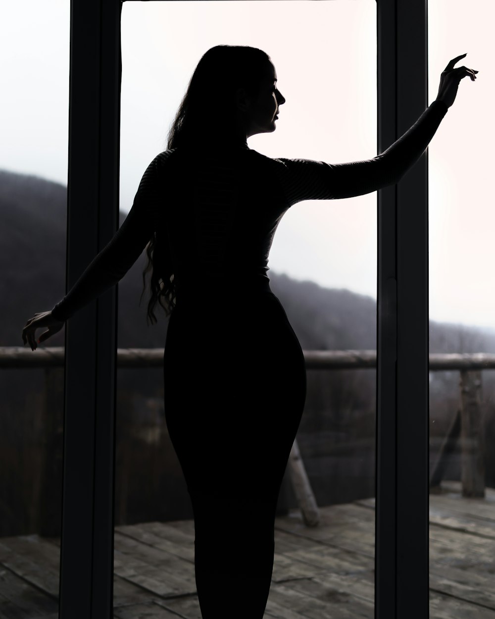 woman in black dress standing by the window