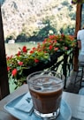 clear drinking glass with brown liquid on white table