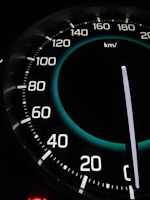 A close-up view of a car speedometer displaying speeds with increments from 20 to 220 kilometers per hour. The needle is pointing at zero, and there is a lit element indicating an empty or off state.