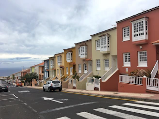 white car parked beside beige concrete building during daytime