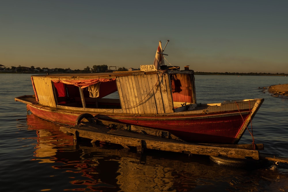 日没時の水面に浮かぶ茶色と赤のボート