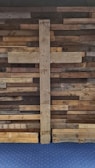Driftwood brown textured wall with a delicate gold cross hanging.