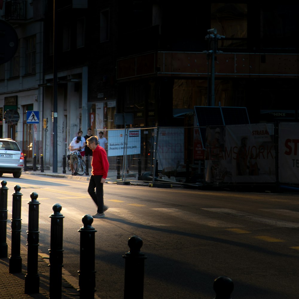 man in red jacket walking on pedestrian lane during daytime