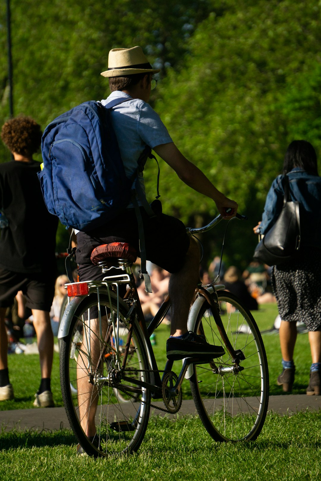 man in blue shirt and black backpack riding bicycle