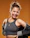 Portrait of a joyful woman wearing a copper-accented Velvara t-shirt against a matte black background.