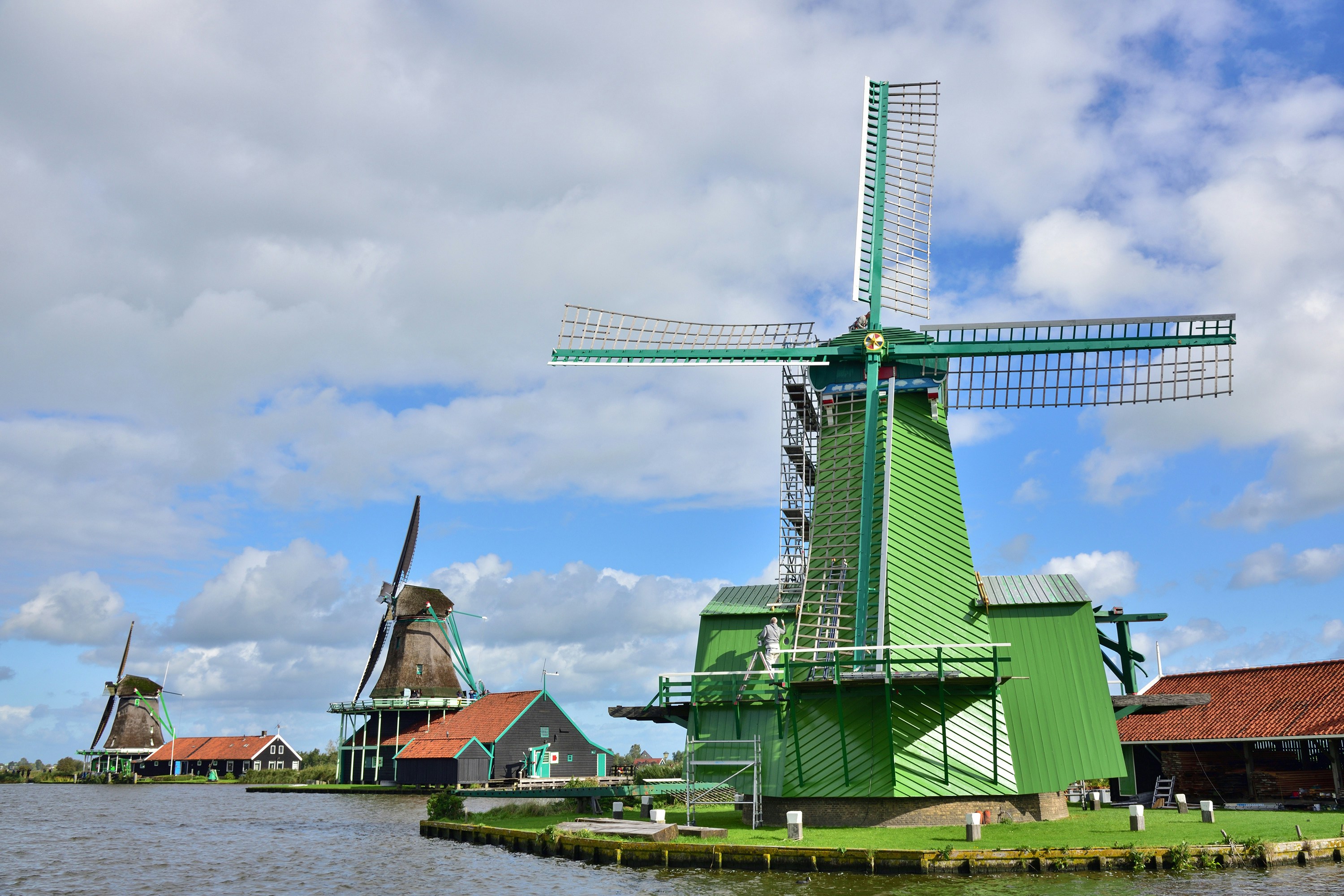 green and brown windmill near body of water during daytime