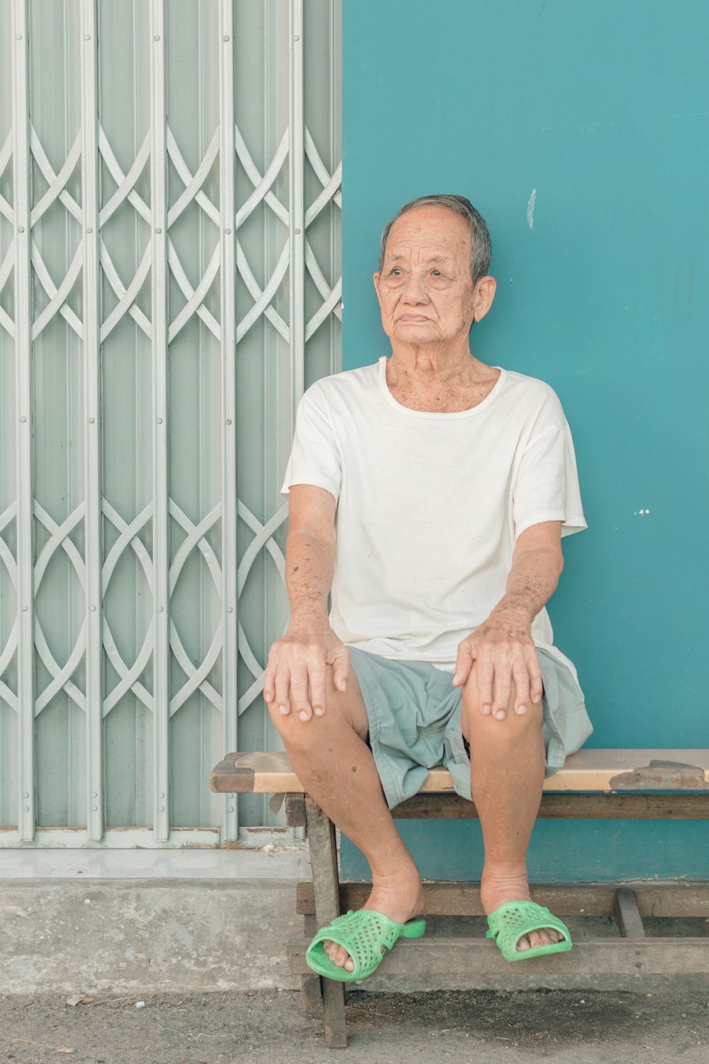 man in white crew neck t-shirt sitting on brown wooden bench