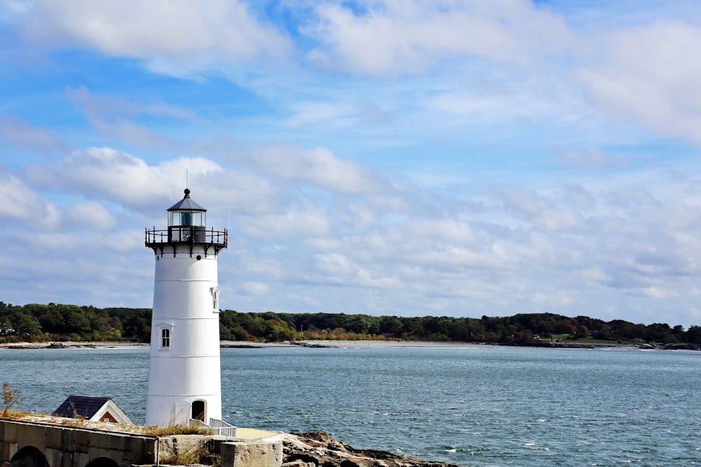 white and black lighthouse near body of water during daytime