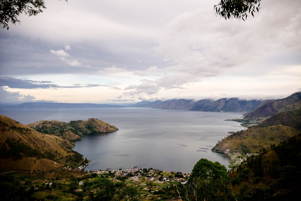 árboles verdes cerca del lago bajo nubes blancas durante el día