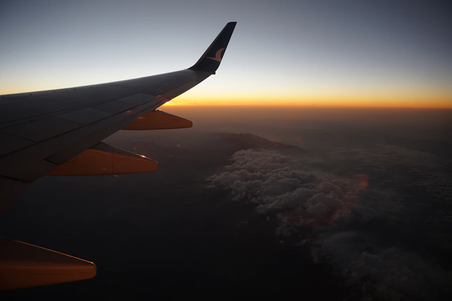 Airplane wing soaring above the clouds