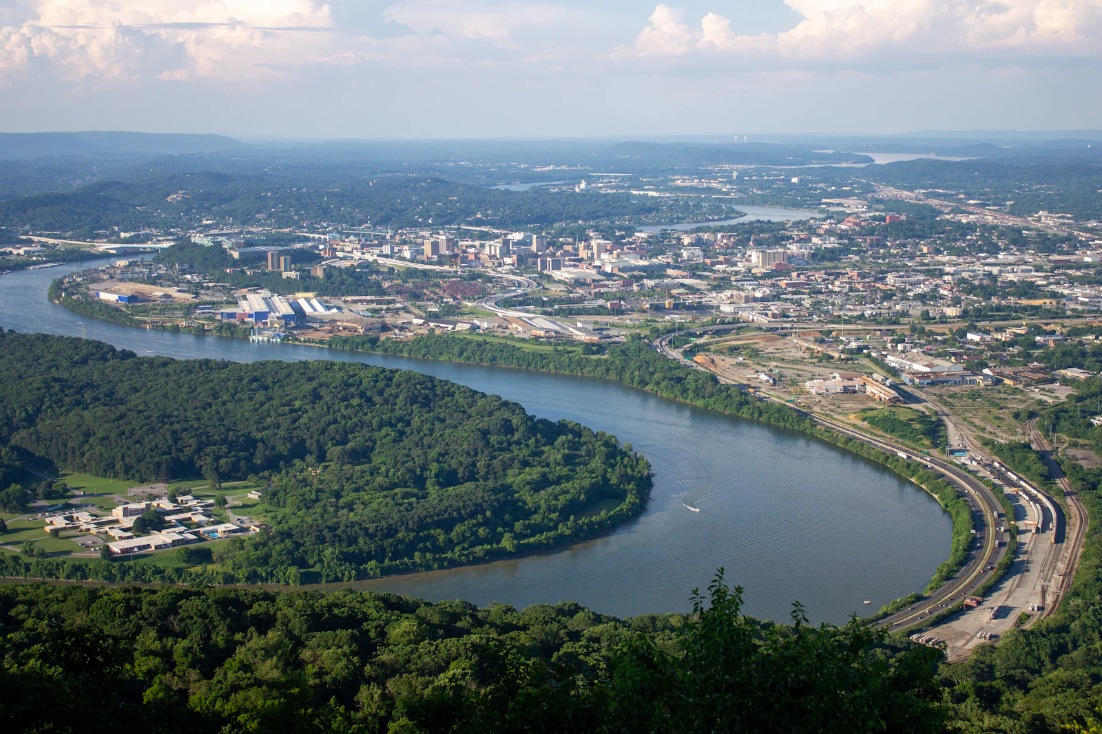An aerial view of a river town among wooded hills.