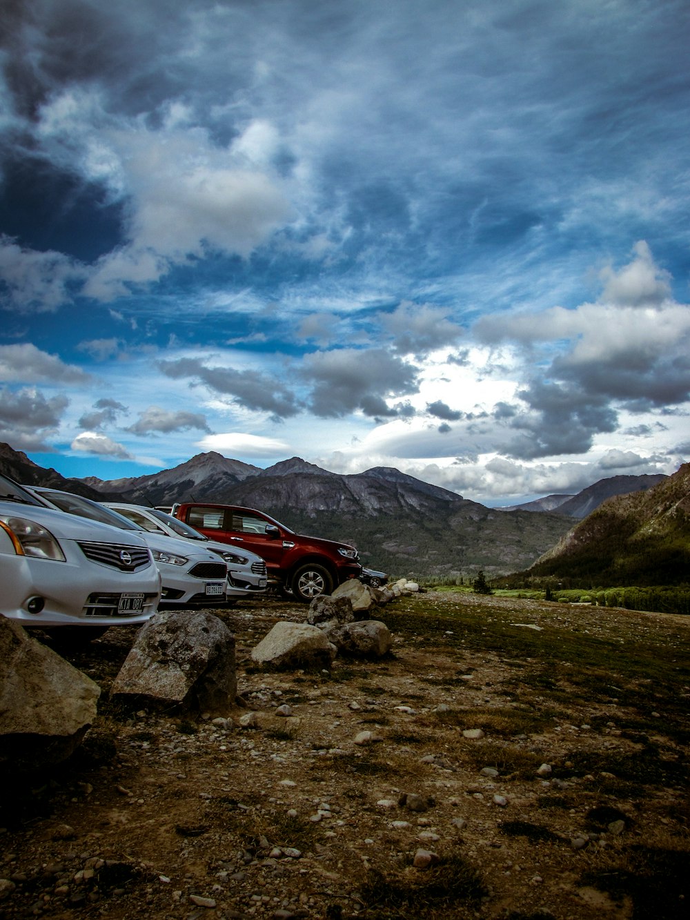 white bmw car on green grass field near mountain under white clouds and blue sky during