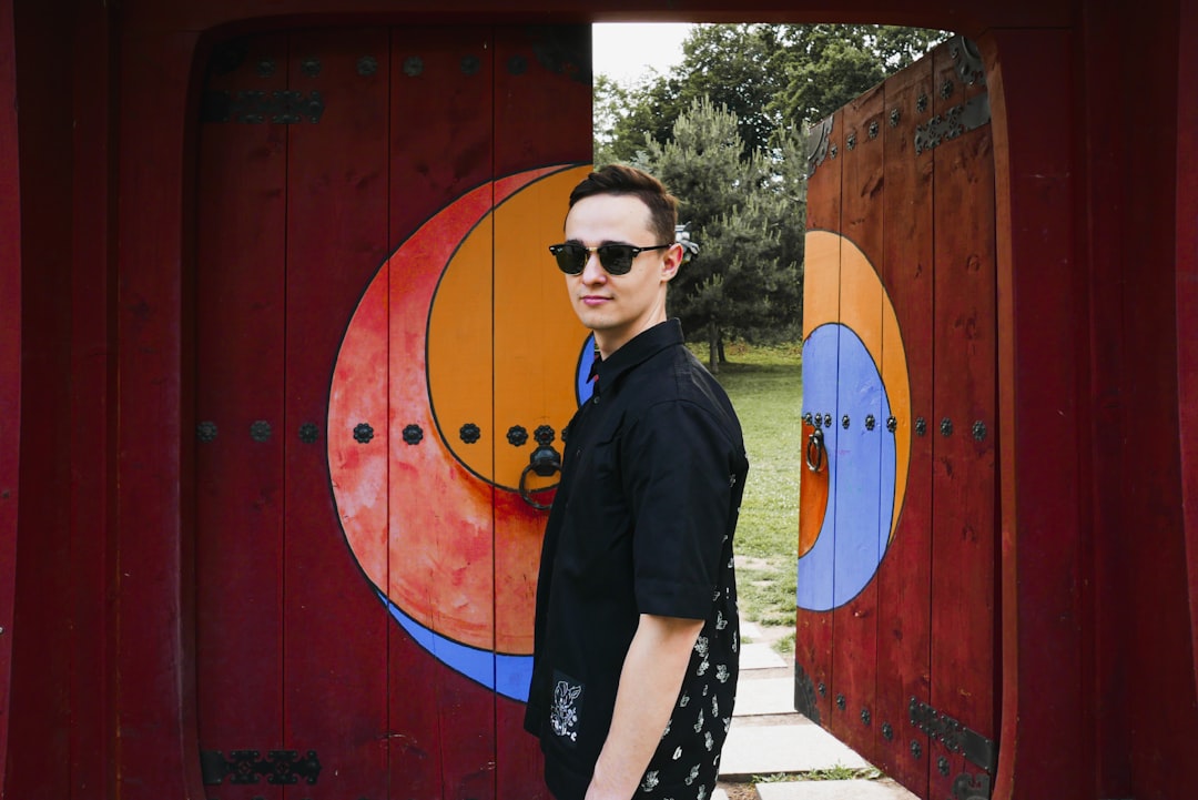 man in black button up shirt standing beside red wall