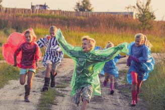 boy in green jacket and red shirt running on road during daytime